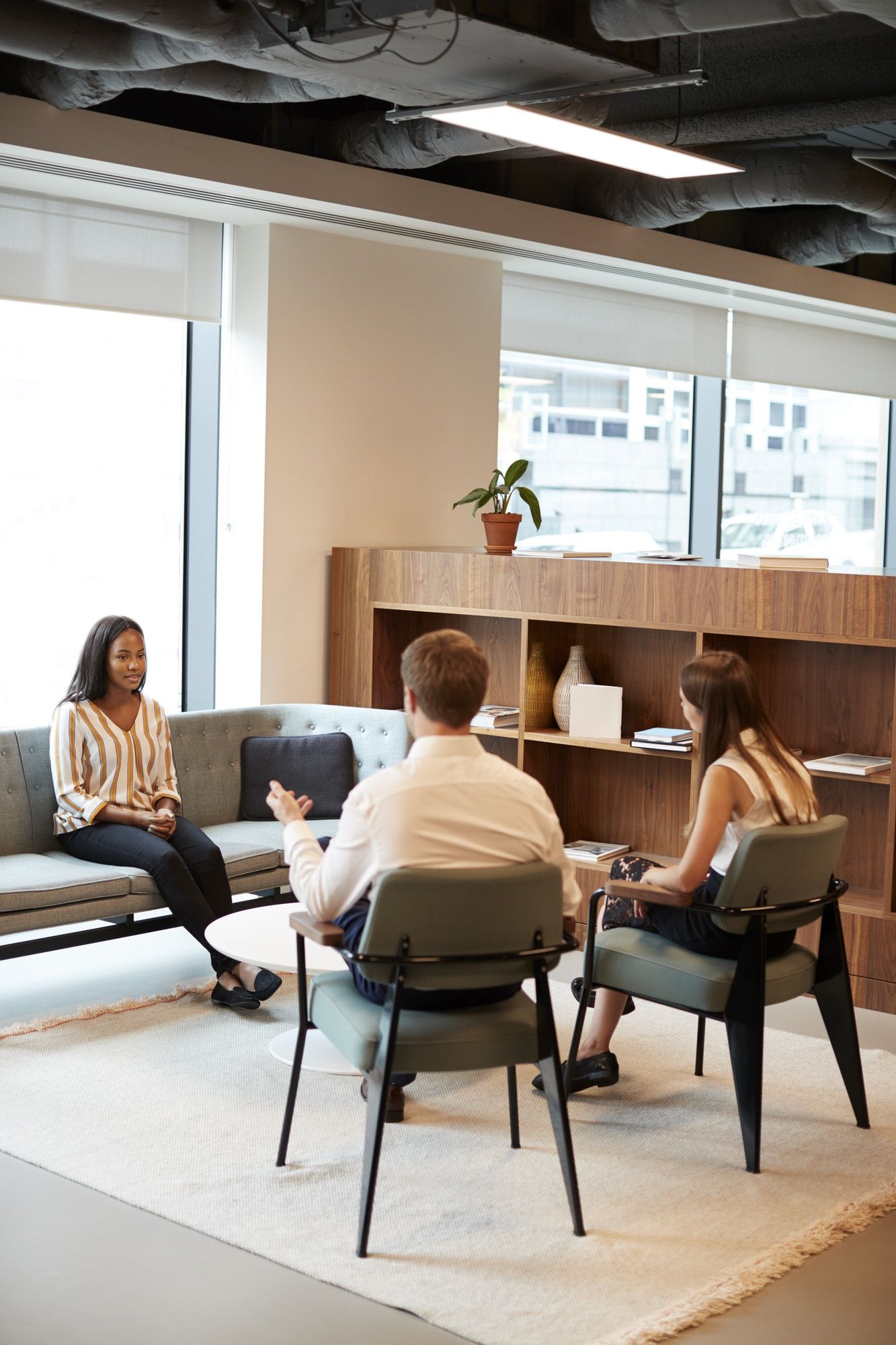 Businessman And Businesswoman Interviewing Female Candidate In Office